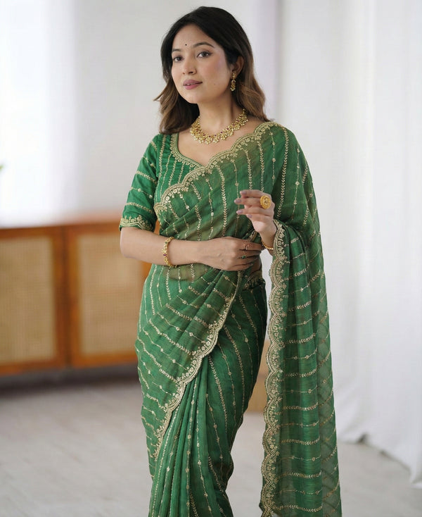 Woman wearing a green saree with gold patterns against a white background