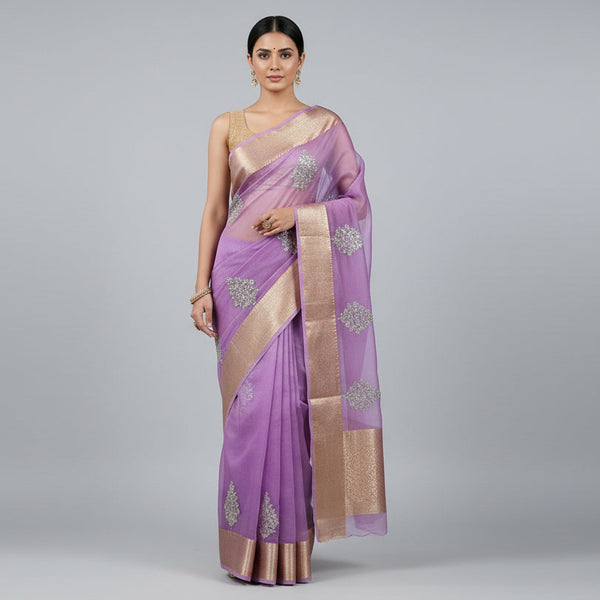 Purple saree with silver floral patterns and a gold border, draped over a surface.