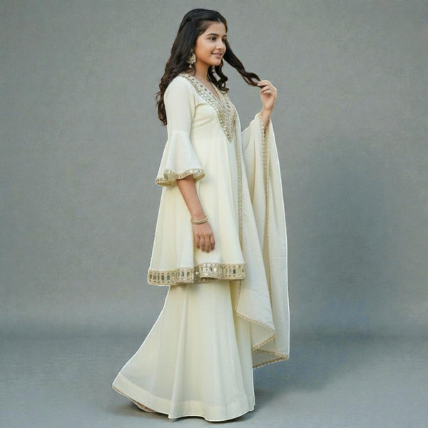 Woman in a cream traditional outfit with gold embroidery on a gray background